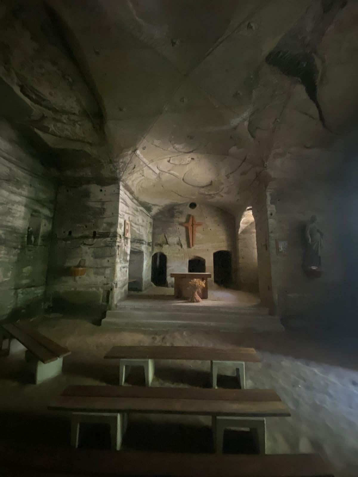 In den Fels gehauene Kapelle mit Holzbänken, Altar und Kreuz