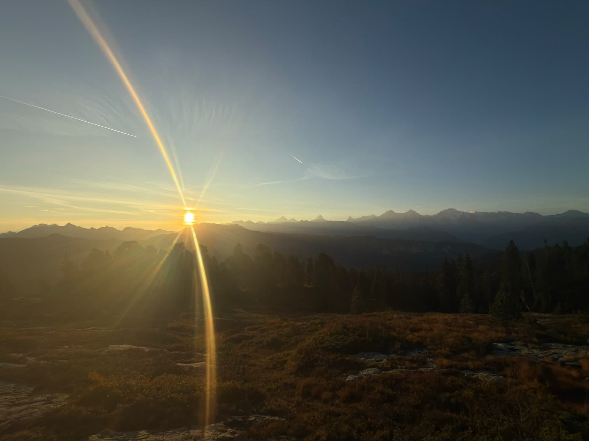 Sonnenaufgang über einer Bergkette, die Sonne steht knapp über dem Horizont
